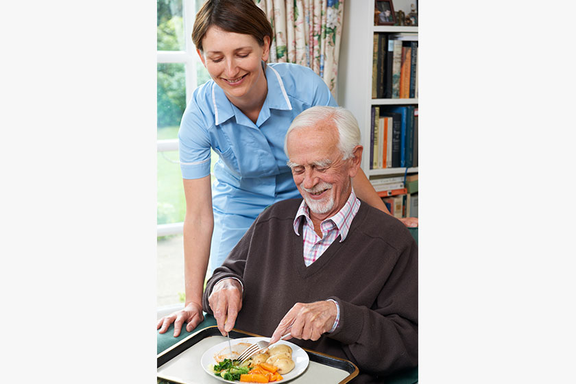 Carer Serving Lunch To Senior Man