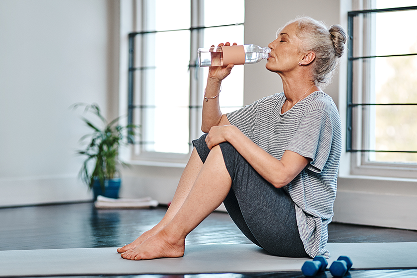 bottoms-mature-woman-practicing-yoga-while-having-drink-water