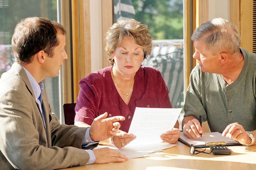 Mature couple talking to financial planner at home