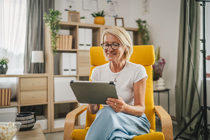 Mature senior woman sit at home and use tablet