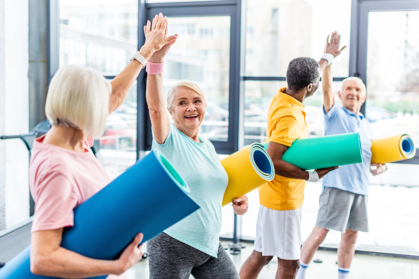 smiling-senior-multiethnic-sportspeople-fitness-mats-taking-high-fives